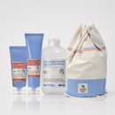 Kit solare Davines SU/ su sfondo bianco con due tubetti blu di crema solare e doposole una bottiglia bianca di shampoo doposole e una borsa a sacco crema e azzurra a strisce arancioni e blu, con etichette che menzionano estratti di arancia amara e mirto da Avola Siracusa e Sardegna Italia