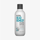 Foto di prodotto del flacone bianco di shampoo KMS Head Remedy Deep Cleanse Purifiant con tappo grigio scuro scritte principali blu e nere illustrazione di foglie stilizzate turchesi e grigie e l'indicazione di frassino riciclato su sfondo chiaro